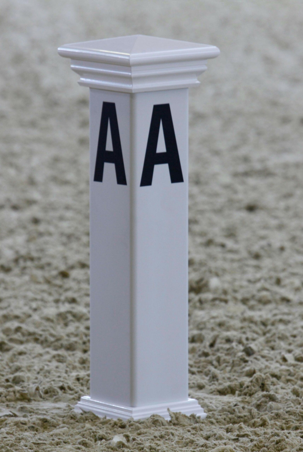 Poste branco com letras AA em superficie de areia clara