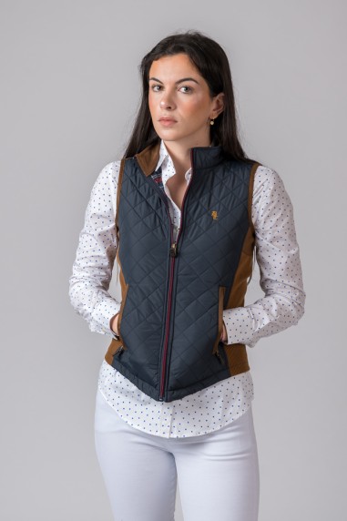 Colete acolchoado preto com detalhes castanhos usado com camisa branca de pontos e calças brancas