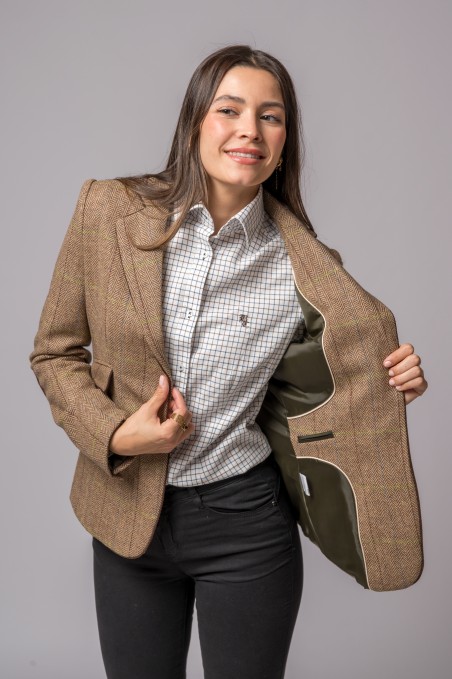 Mulher a vestir blazer castanho riscado com interior verde oliva, camisa branca quadriculada e calças pretas