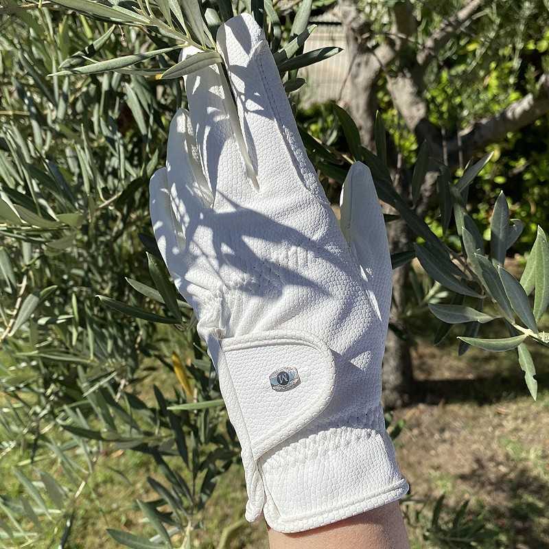 Luva branca de tecido com fecho de velcro usada numa mão em ramo de oliveira ao ar livre