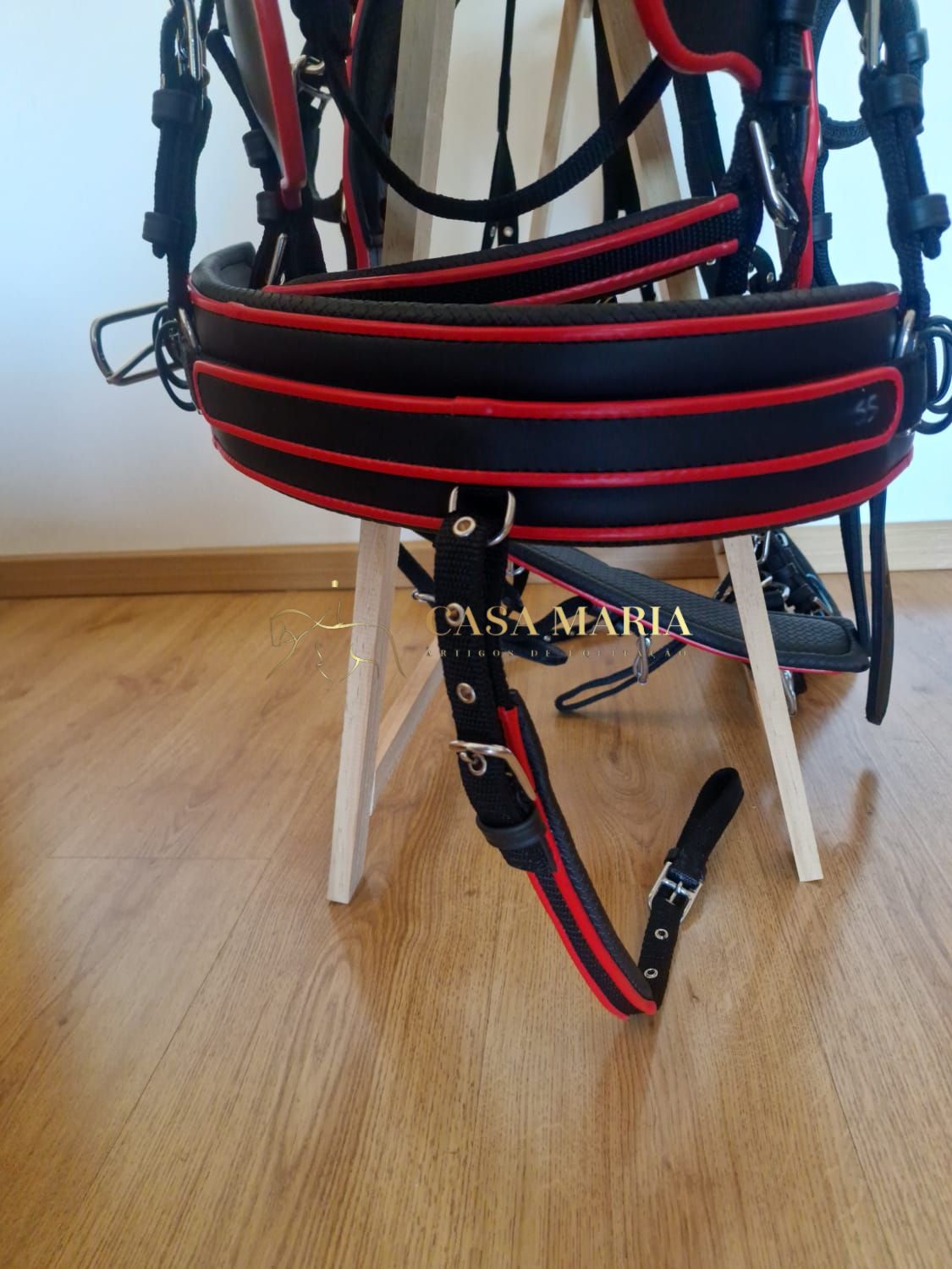 Sela preta com detalhes vermelhos pendurada em cadeira de madeira clara