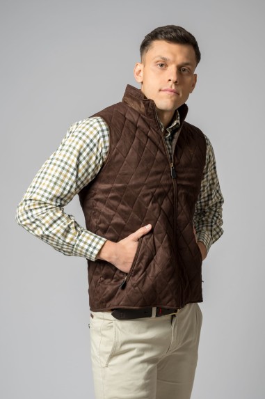 Homem com colete acolchoado castanho e camisa às quadrículas