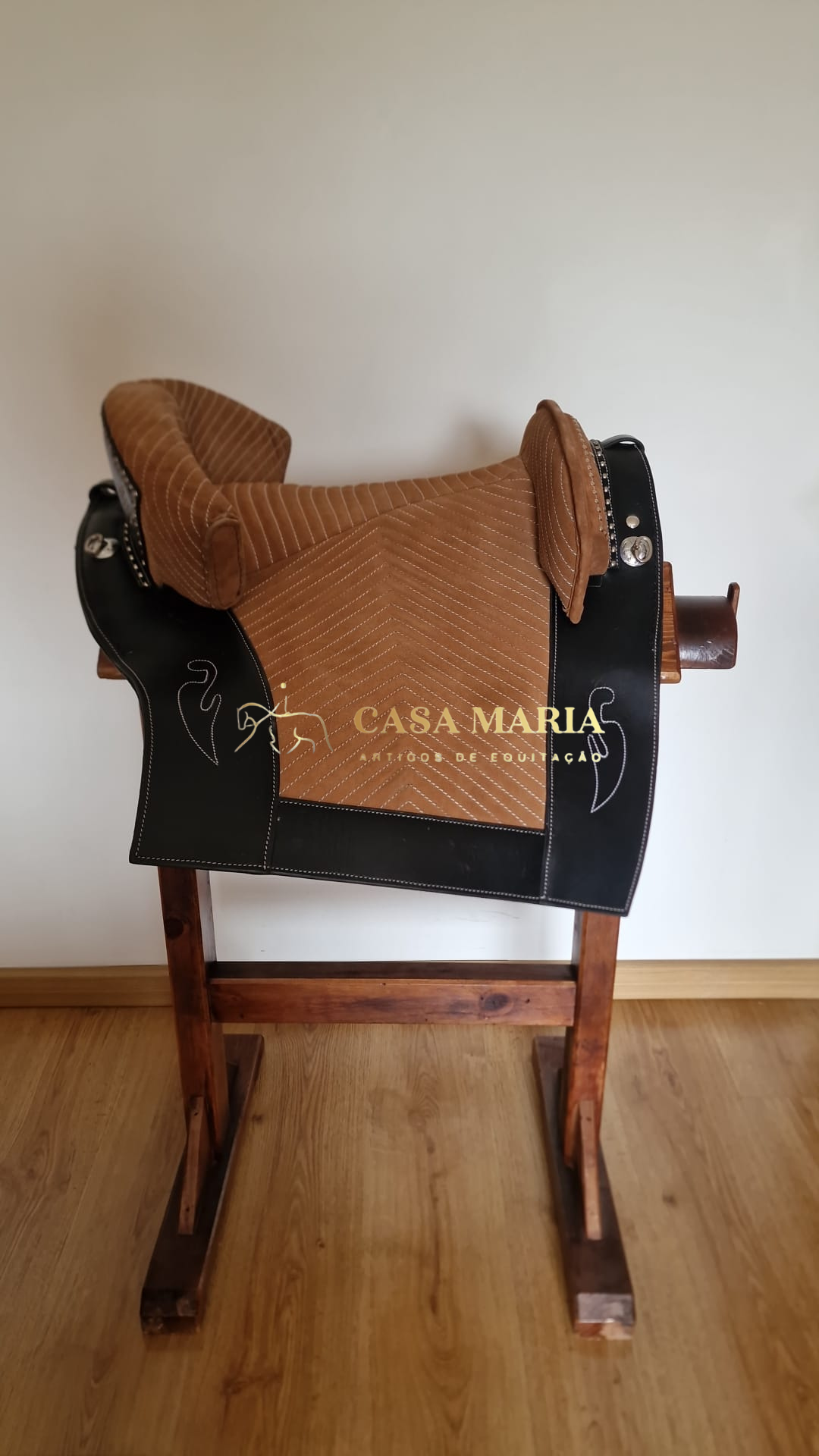 Sela de equitação castanha e preta num suporte de madeira