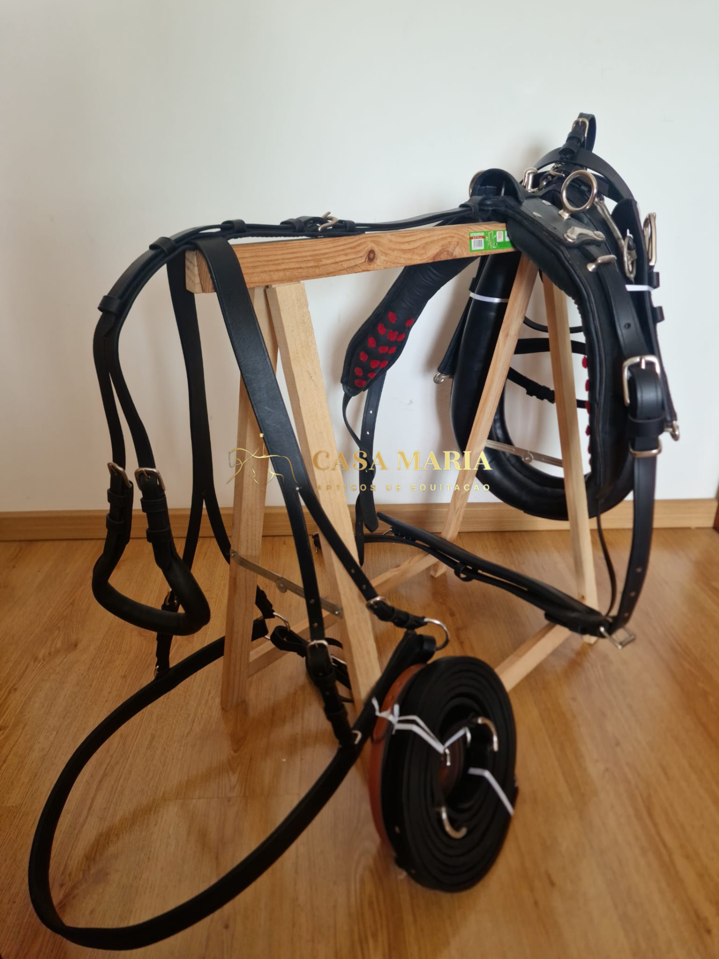 Equipamento de equitação em couro preto pendurado em suporte de madeira