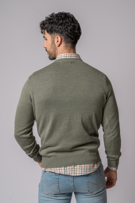 Homem de costas a usar camisola verde e camisa xadrez com calças de ganga azul claro