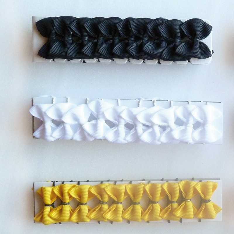 Três conjuntos de pequenos laços de fita preta, branca e amarela em cartões brancos