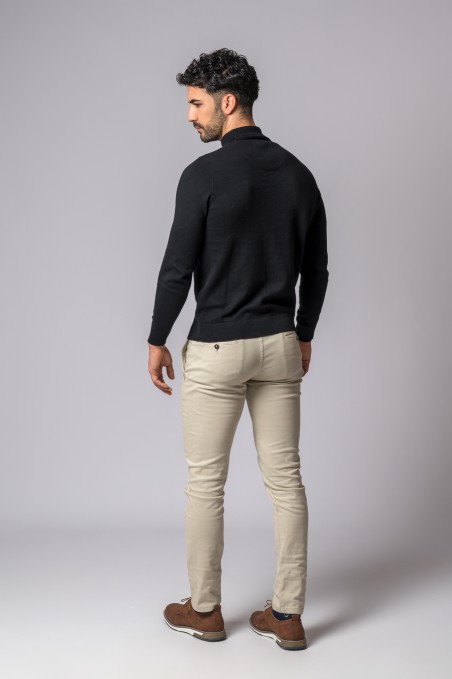 Homem de costas com camisola preta gola alta e calças bege