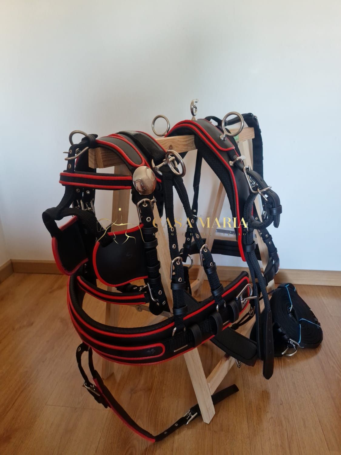 Arnês de couro preto com detalhes vermelhos e fivelas metálicas