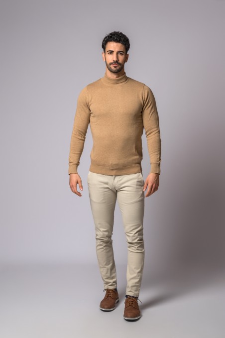 Homem com camisola camel de gola alta, calças bege e sapatos castanhos