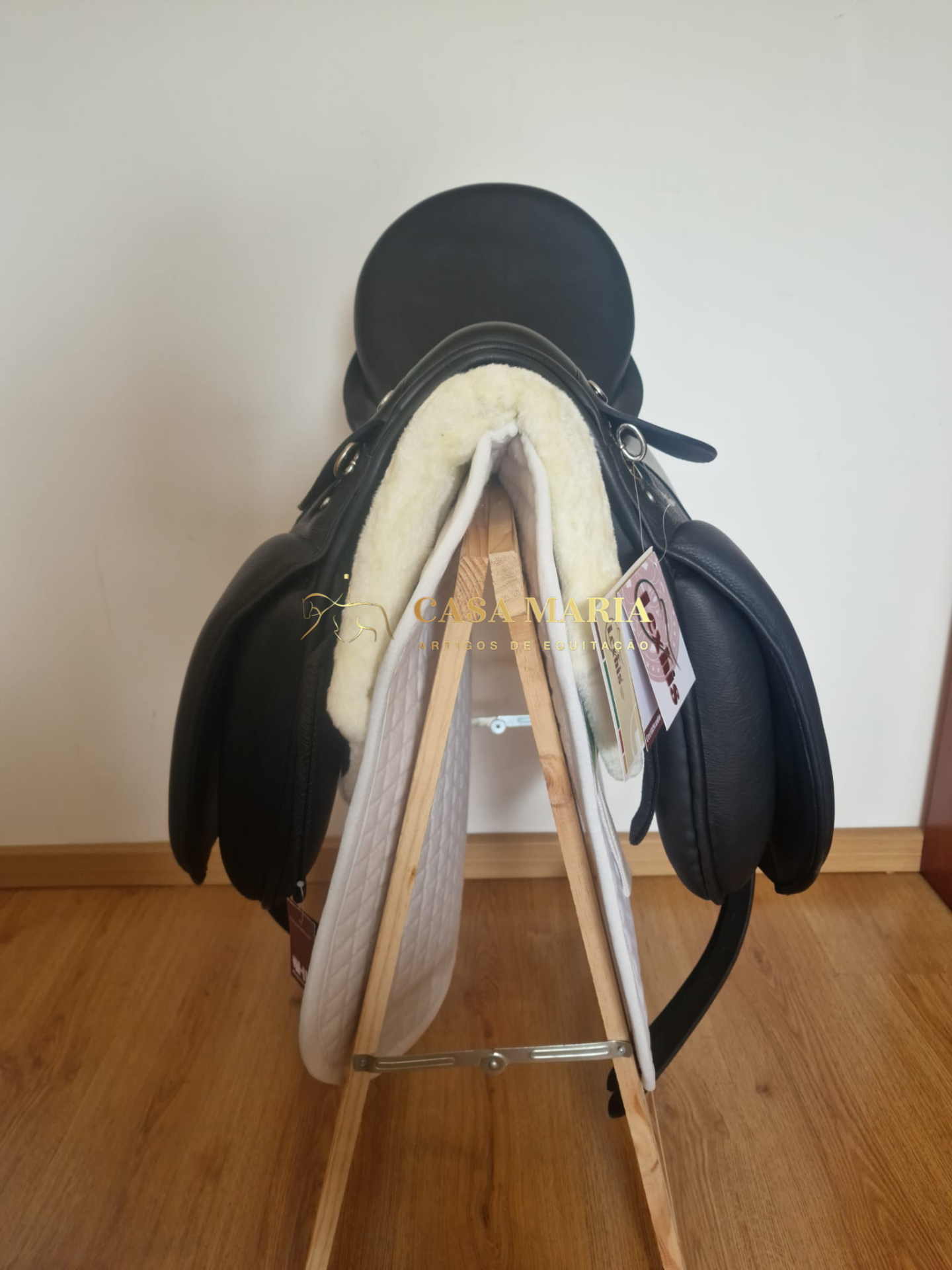 Sela de equitação preta com interior acolchoado em lã branca numa estrutura de madeira
