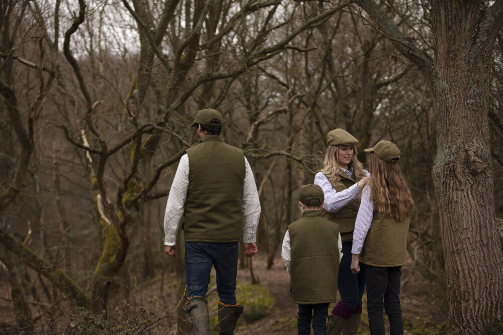Quatro pessoas com coletes verdes e camisas xadrez em floresta sem folhas