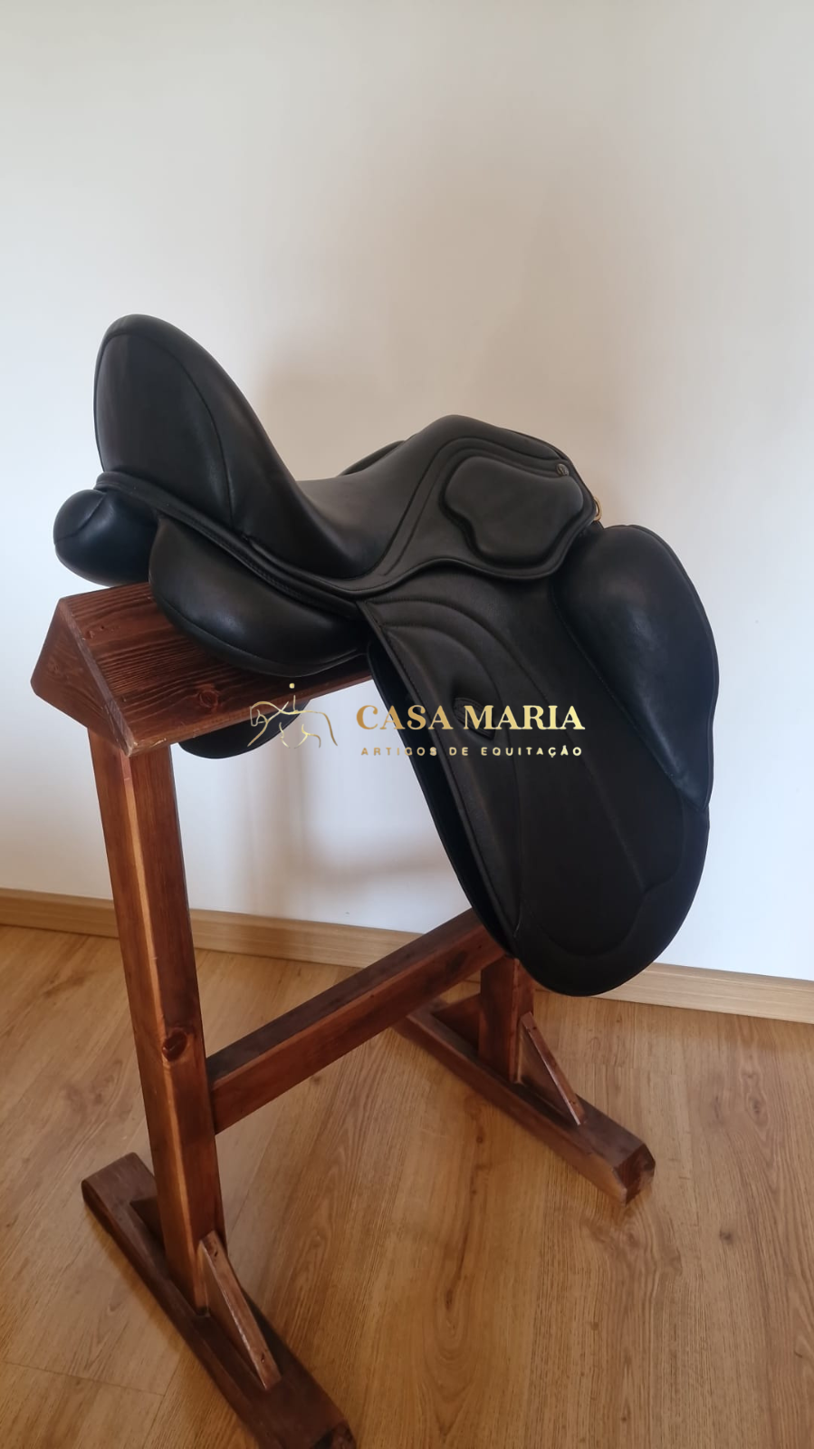 Sela de equitação preta em couro sobre suporte de madeira