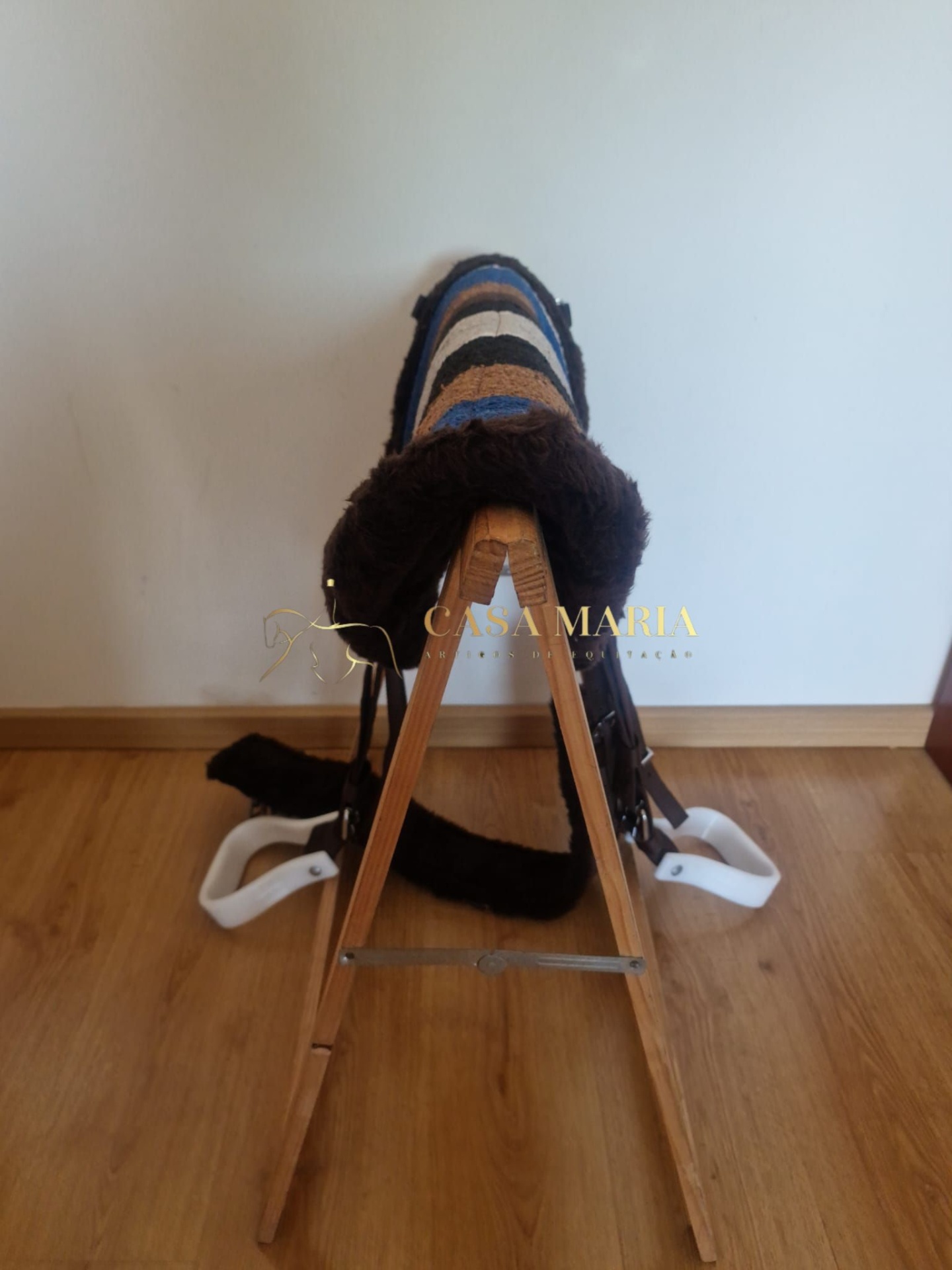 Sela de equitação multicolorida com acabamento felpudo numa estrutura de madeira