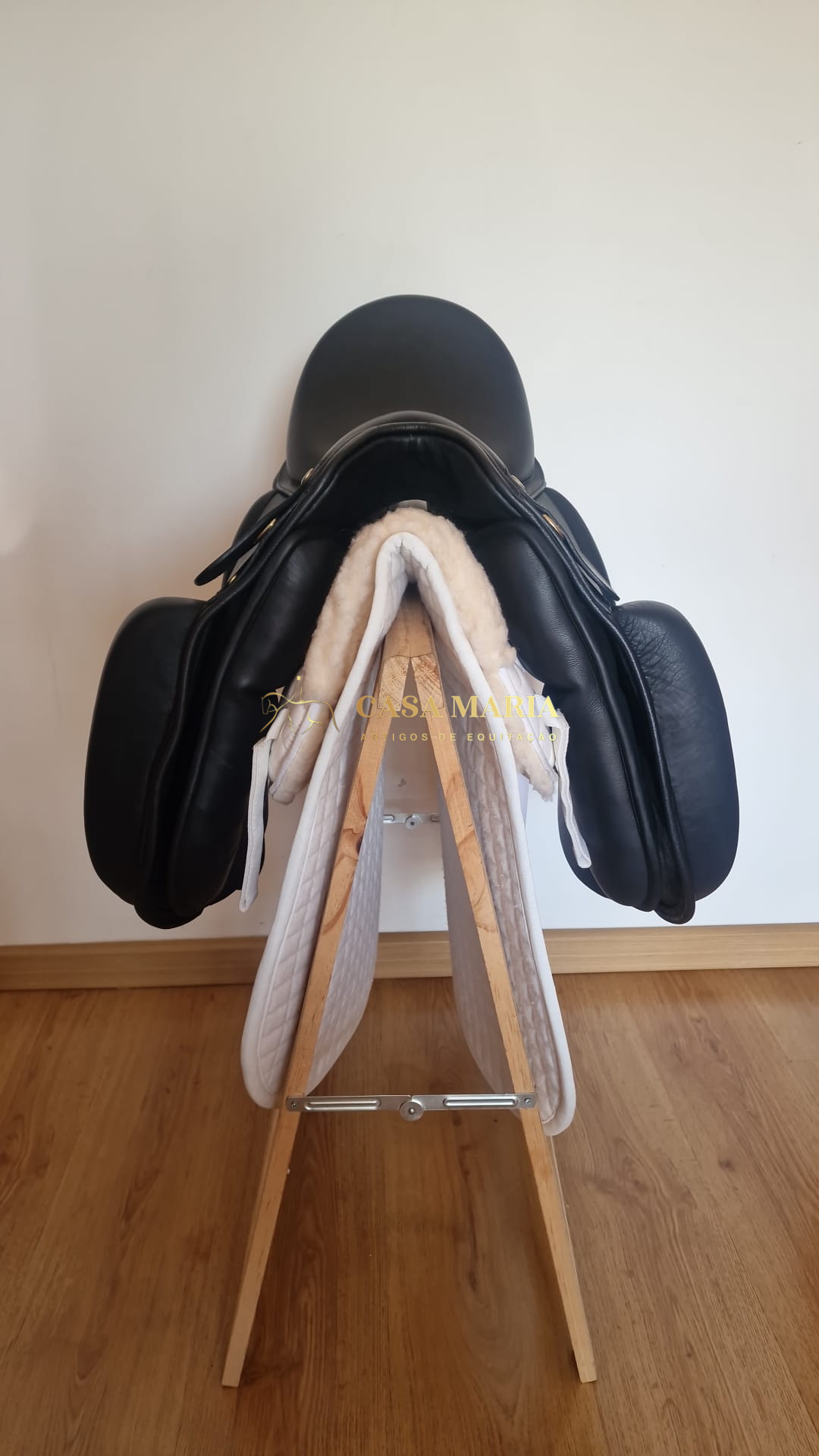 sela de equitação preta em couro com mantilha branca e suporte de madeira