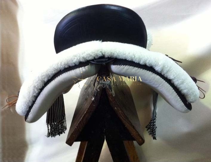 Sela de cavalo em couro preto com acolchoamento branco sobre suporte de madeira