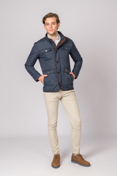 Homem com casaco azul escuro acolchoado, calças claras e sapatos castanhos