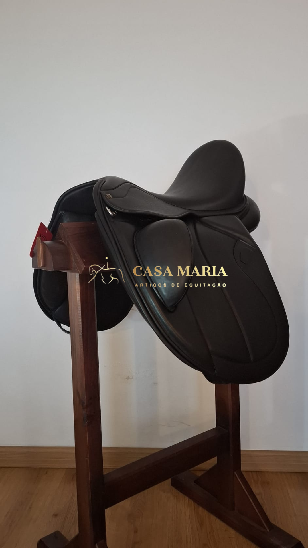 Sela de equitação preta de couro num suporte de madeira