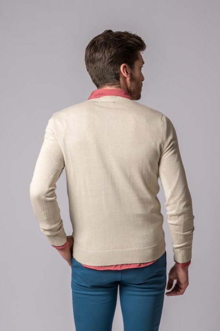 Homem de costas com camisola creme, camisa rosa e calças azuis