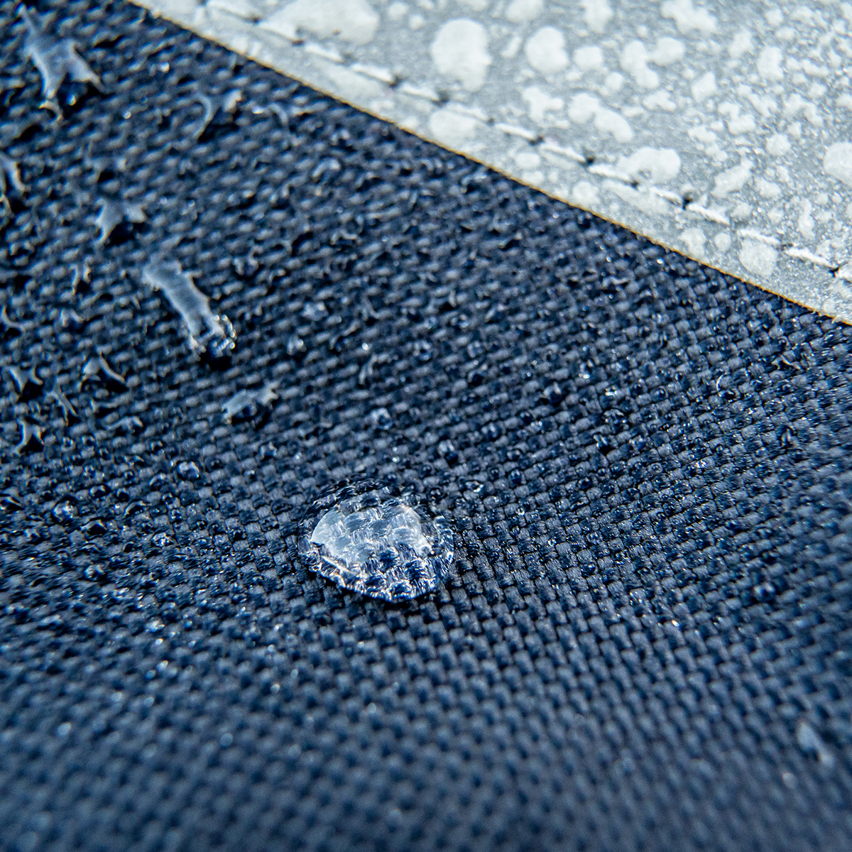 Tecido azul-escuro com gotas de água e faixa cinza com padrão irregular