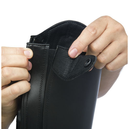 Bota preta de couro com fecho e botão, mostrada em mãos