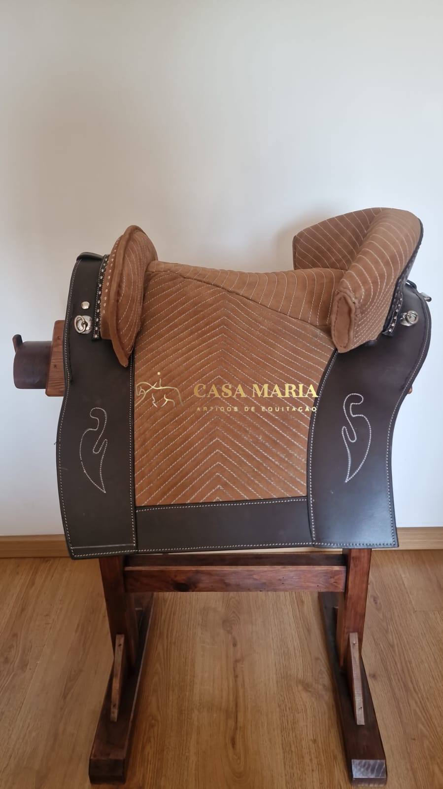 Sela de equitação castanha e bege em suporte de madeira