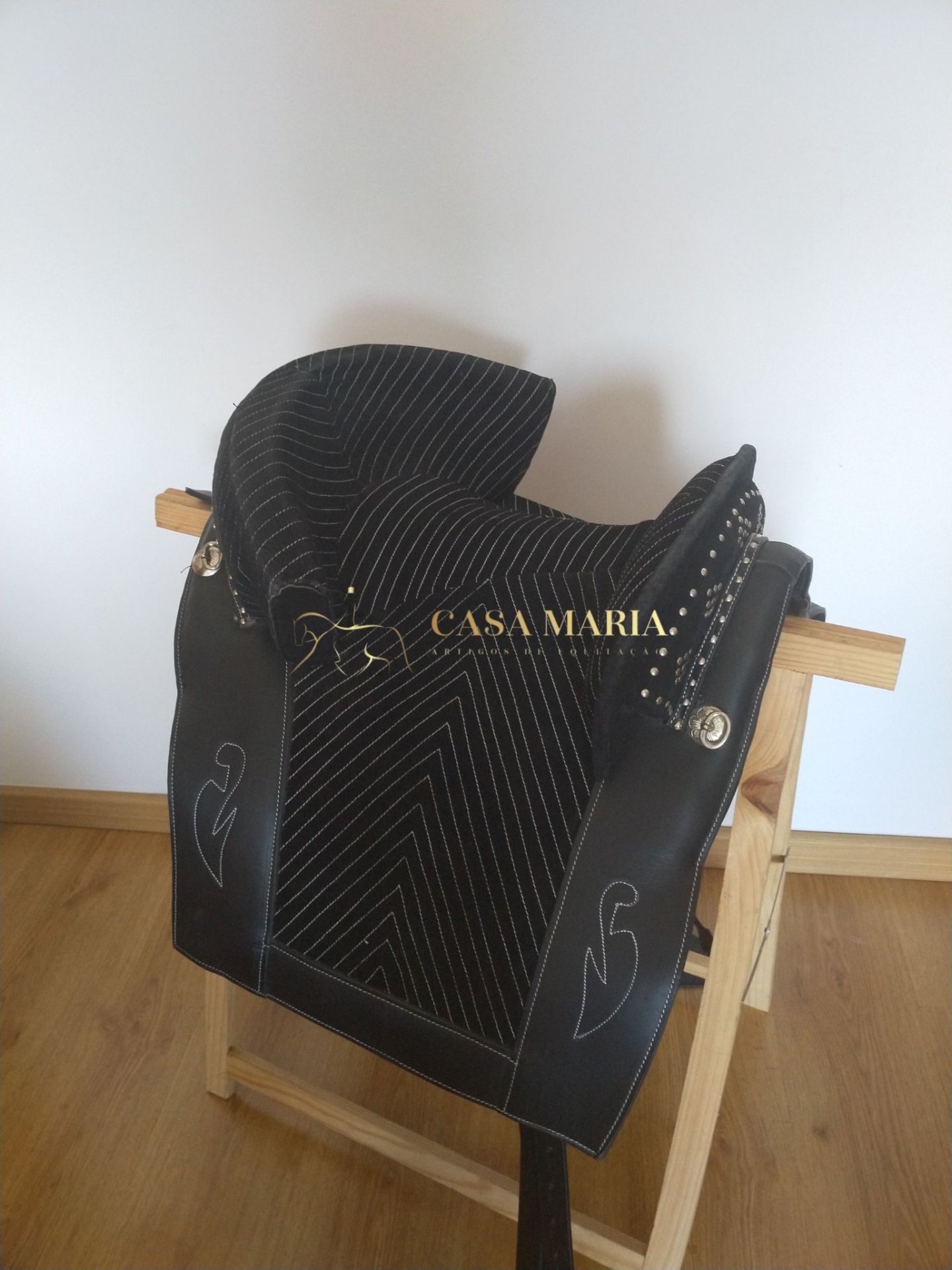 Sela de equitação preta com detalhes brancos e texto CASA MARIA