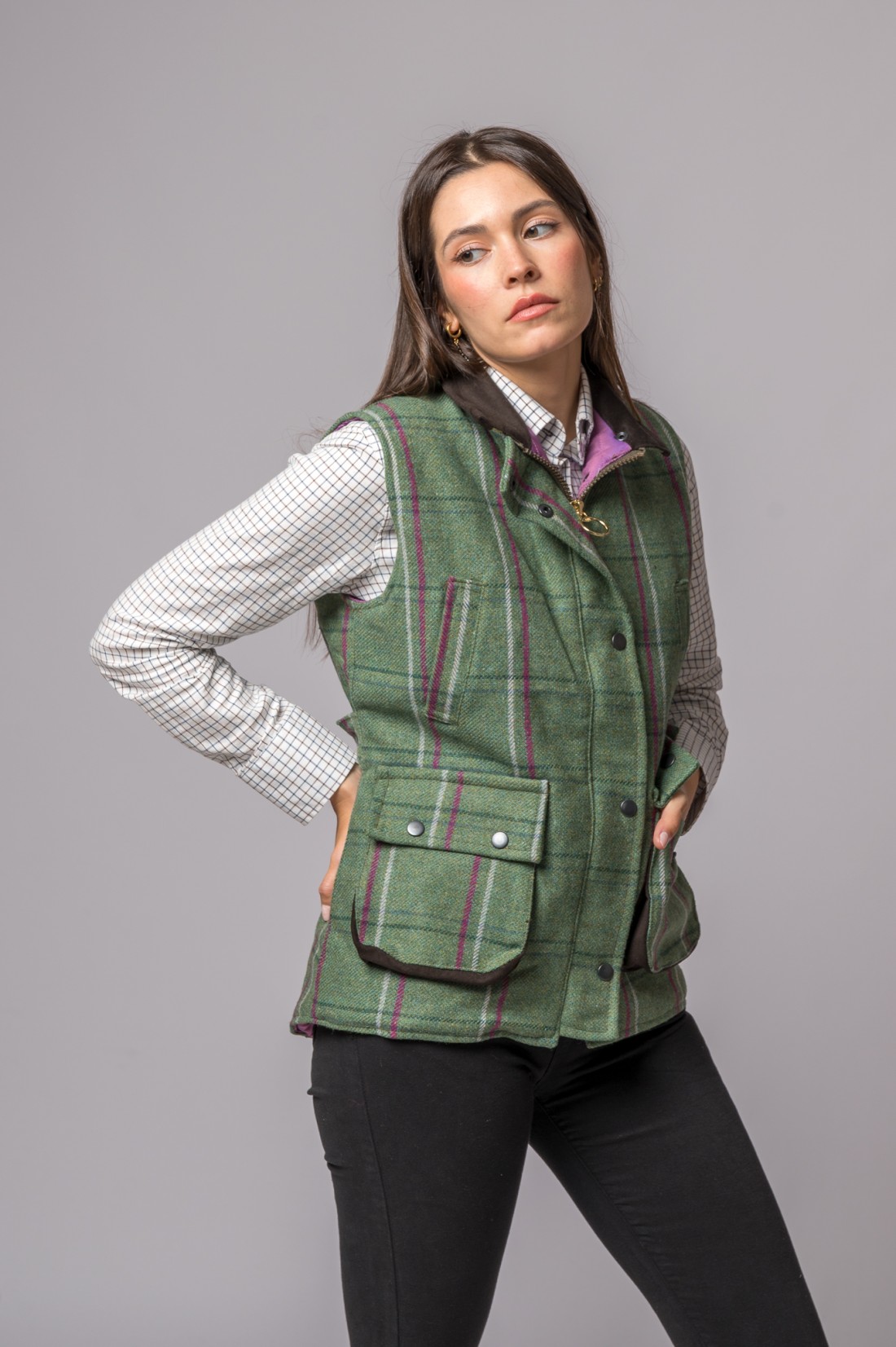 Colete verde às riscas com botões e bolsos, camisa branca e calças pretas, modelo mulher