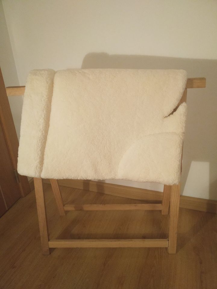 Cobertor de lã bege claro num suporte de madeira