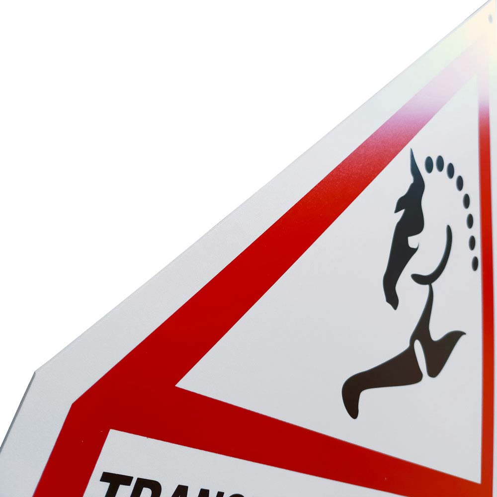 Placa de trânsito triangular com símbolo preto de uma pessoa a correr e texto TRANS