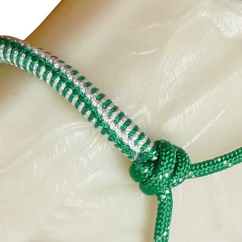 Corda verde com padrão branco formando um nó sobre superfície clara