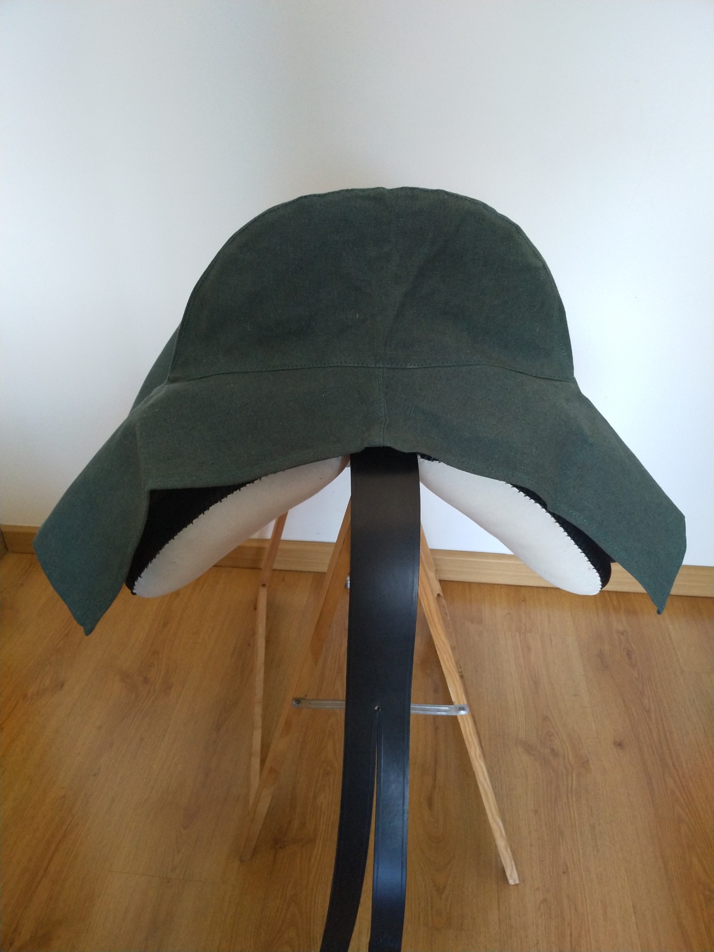 Chapéu verde escuro com aba larga num suporte preto e madeira