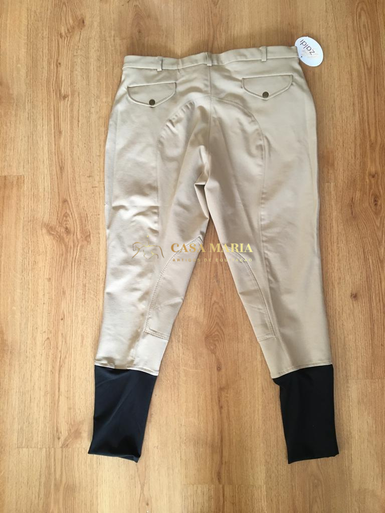 Calças bege de equitação com punhos pretos e bolsos atrás sobre piso de madeira.