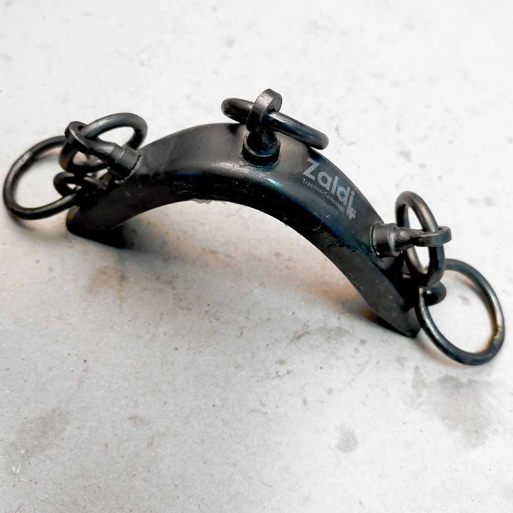 Suporte metálico preto com anéis e parafusos assinalado com Zaldi Tradition+Technology