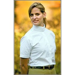 Mulher com camisa branca de gola alta e calças bege ao ar livre