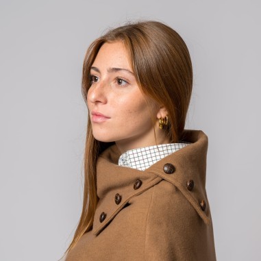 Mulher jovem com capa castanha e camisa branca com padrão de grade