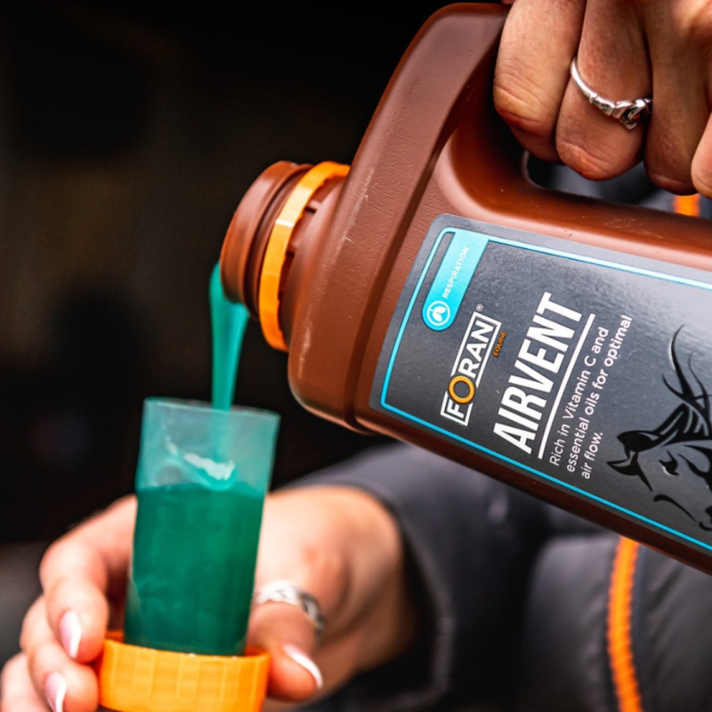 Recipiente castanho com líquido azul esverdeado a ser vertido para um copo laranja transmissível