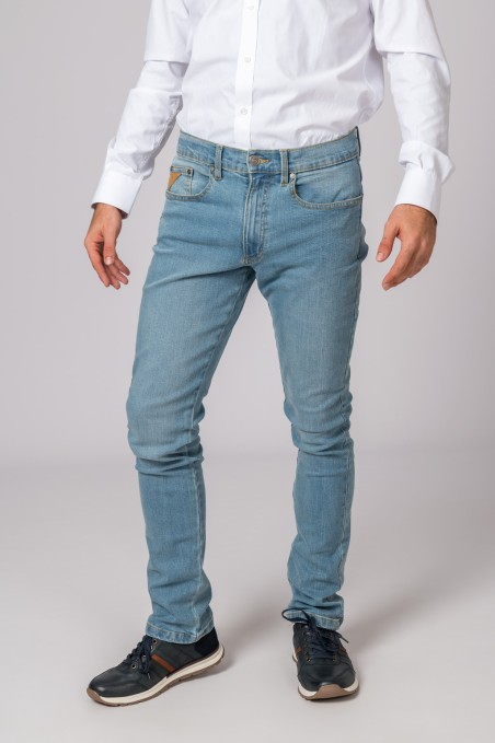 Calças ganga azuis claras em modelo com camisa branca e sapatilhas pretas em fundo neutro