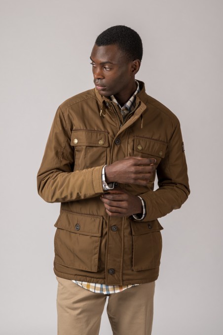 Homem a usar casaco castanho de tecido com bolsos e botões, camisa xadrez e calças bege