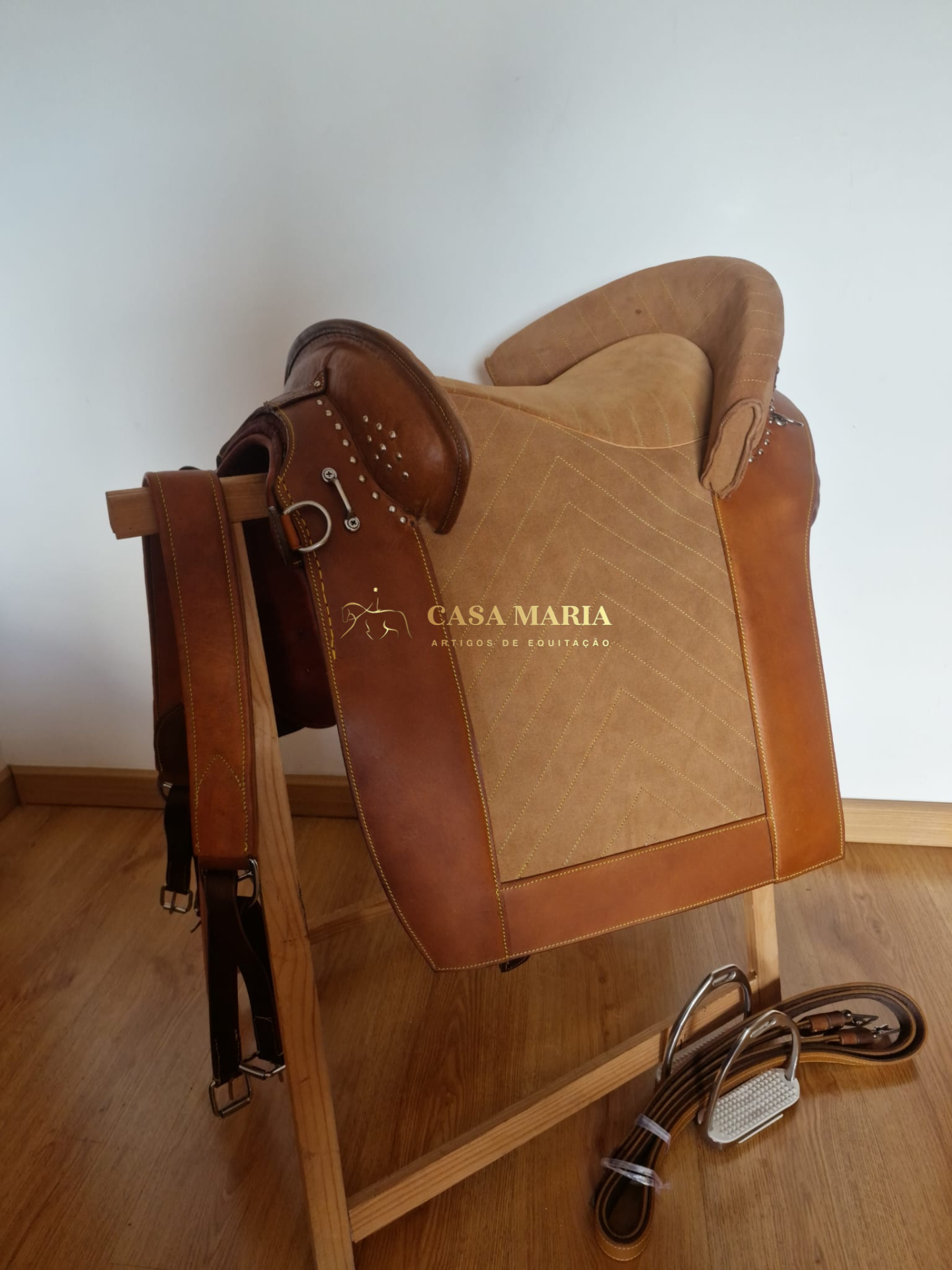 Sela de equitação castanha e bege com textos e acessórios em madeira e couro.