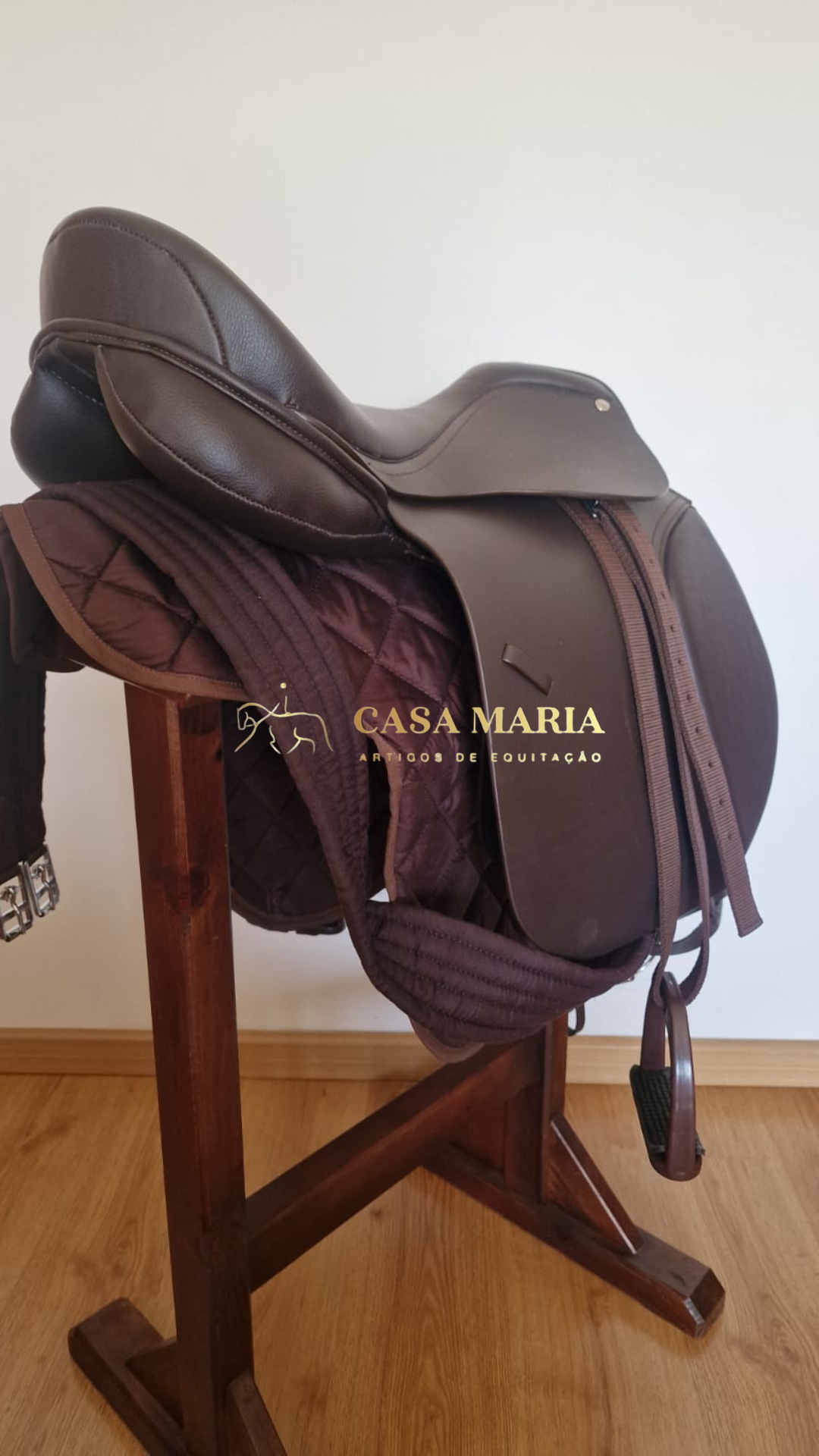 Sela de equitação castanha em couro com mantilha acolchoada castanha em cabide de madeira
