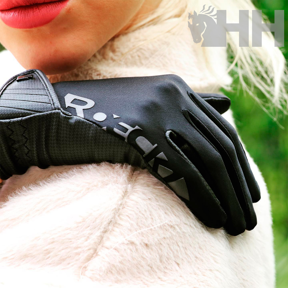 Luva preta com texto R-e:kk usada por pessoa com casaco creme felpudo