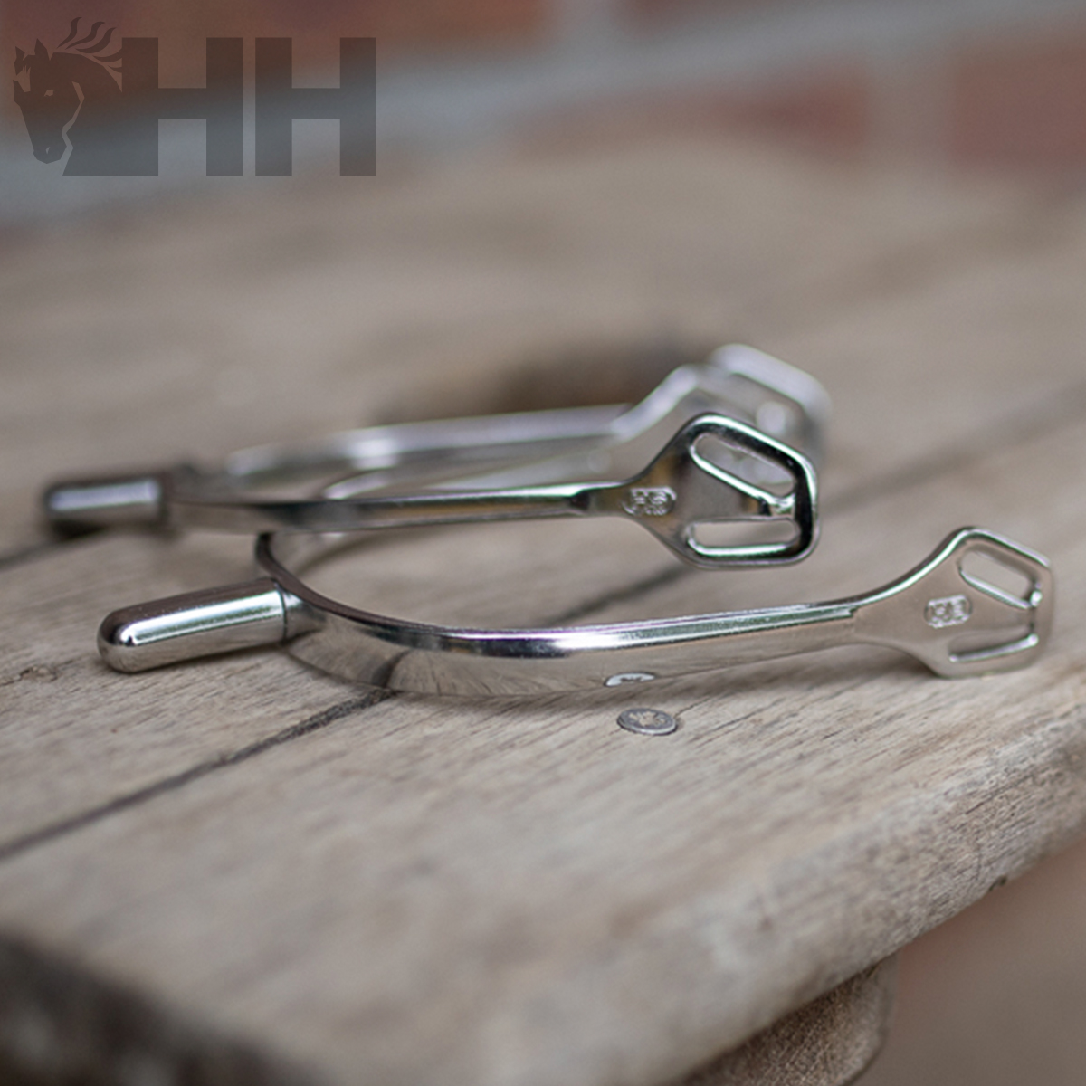 Par de esporas metálicas prateadas sobre madeira rústica