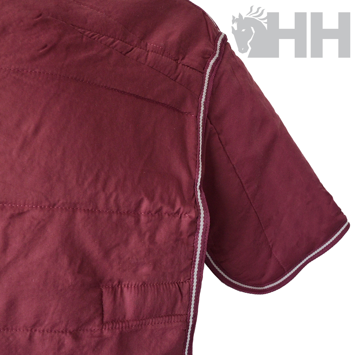 Parte de camisa vermelha com costuras e logo HH cinzento no fundo