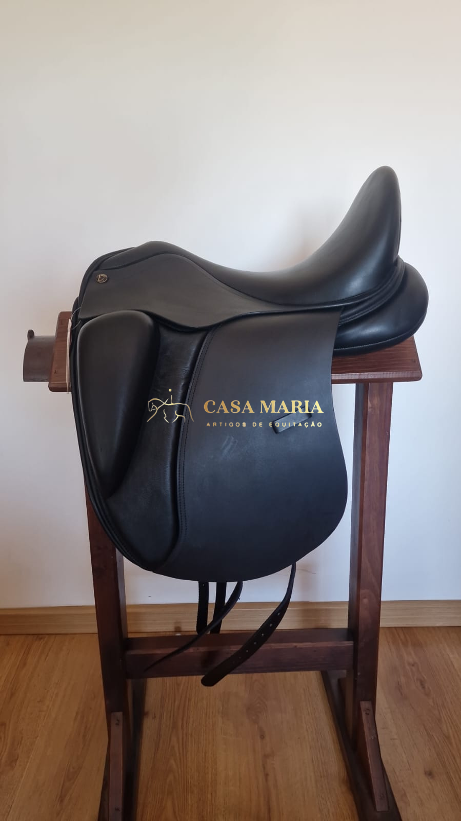 Sela preta de equitação em couro sobre suporte de madeira
