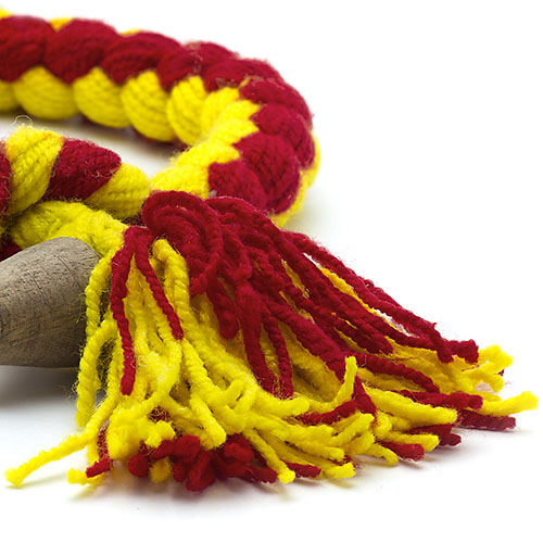 Cordão trançado de lã amarelo e vermelho com franjas e objeto de madeira