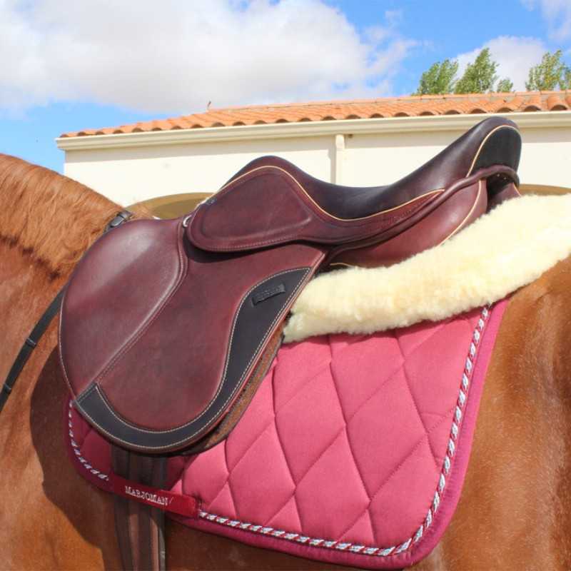 Sela de equitação em couro castanho escuro sobre cavalo com manta vermelha acolchoada com texto MARJOMAN