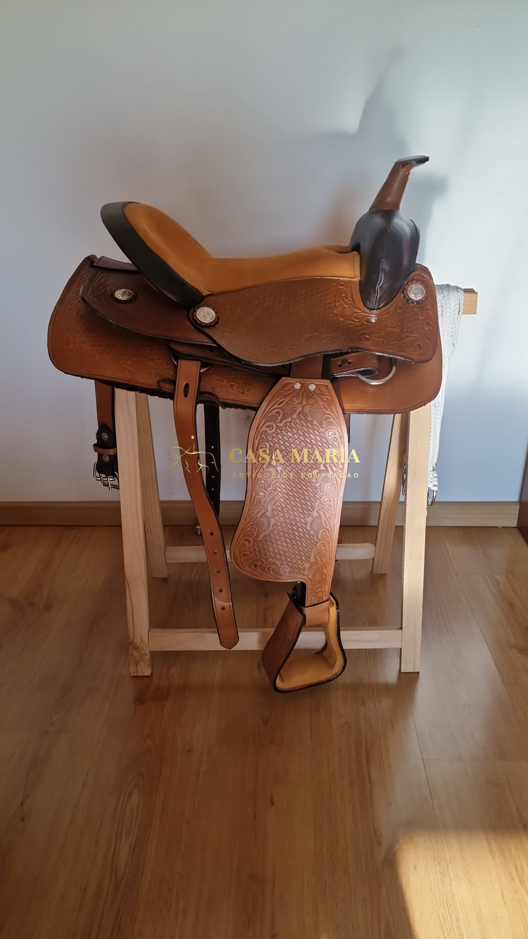 Sela de couro castanho com gravações sobre suporte de madeira interior