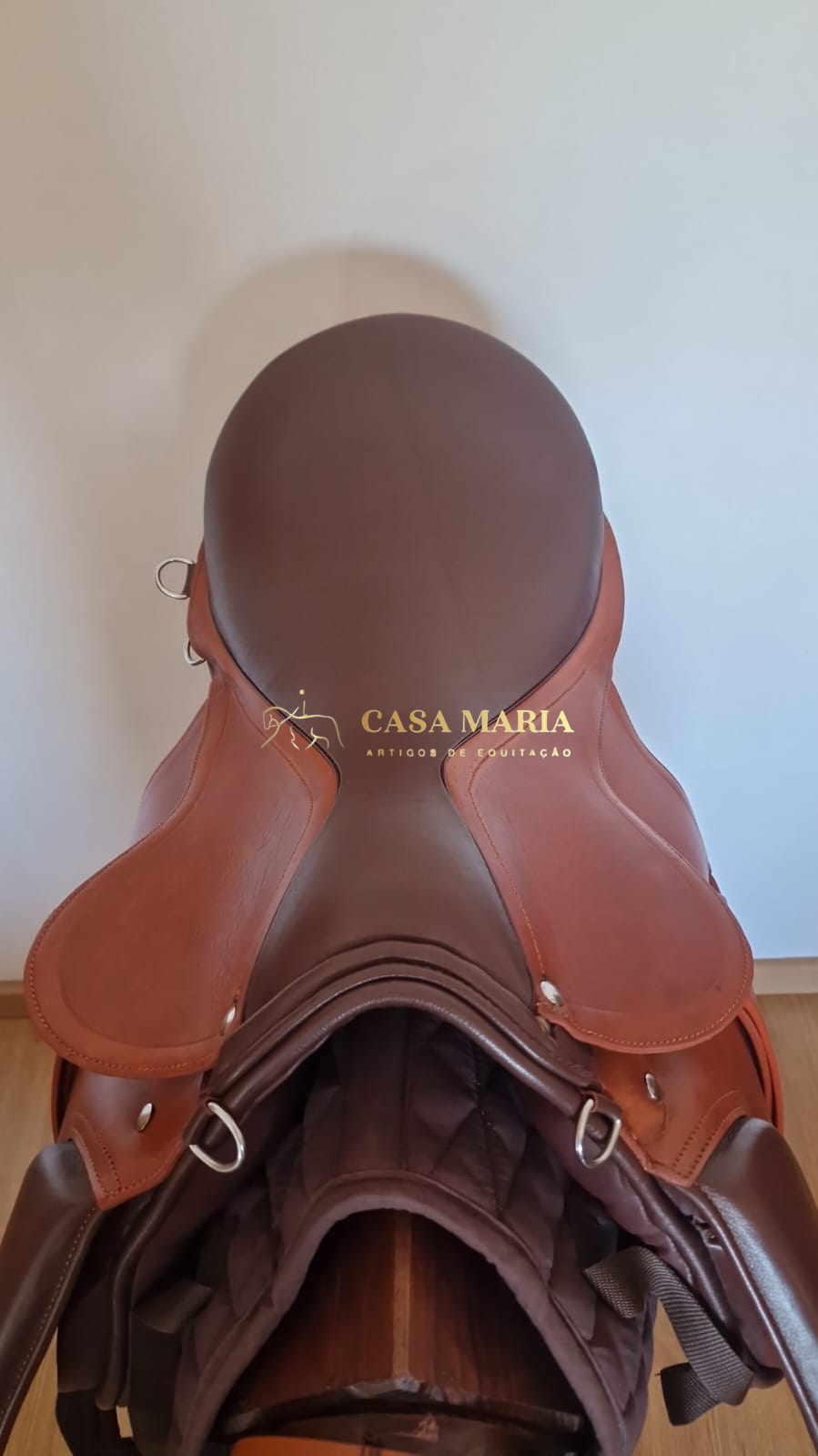 Sela de equitação em couro castanho com texto CASA MARIA ARTIGOS DE EQUITAÇÃO