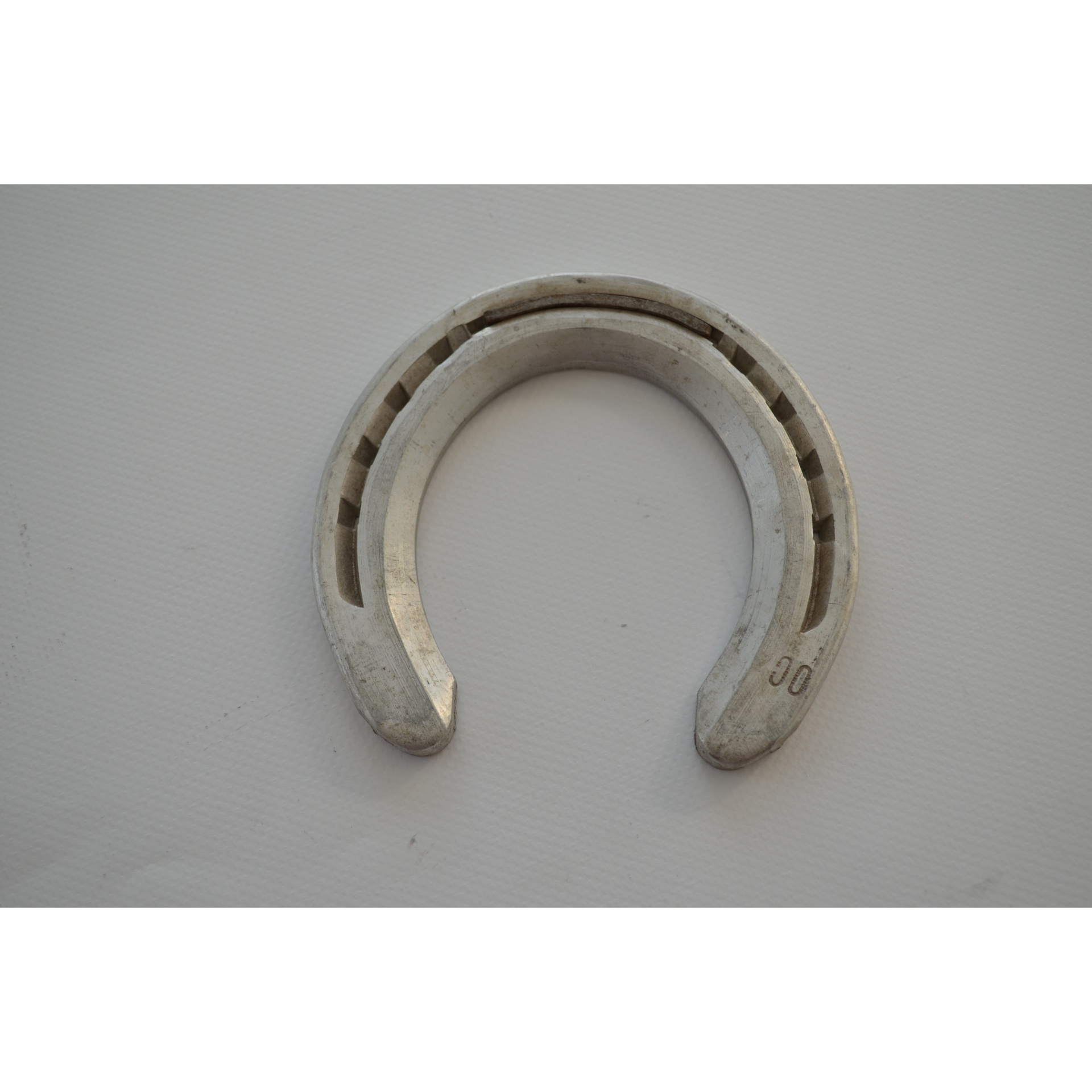 Ferradura metálica cinza com ranhuras e marcação 00