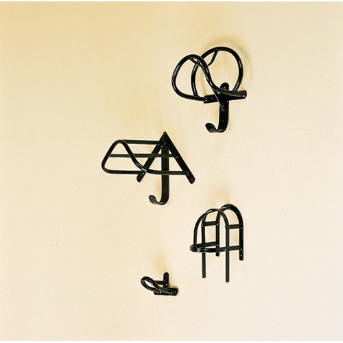 Quatro acessórios de parede pretos em metal de vários designs fixados numa parede creme